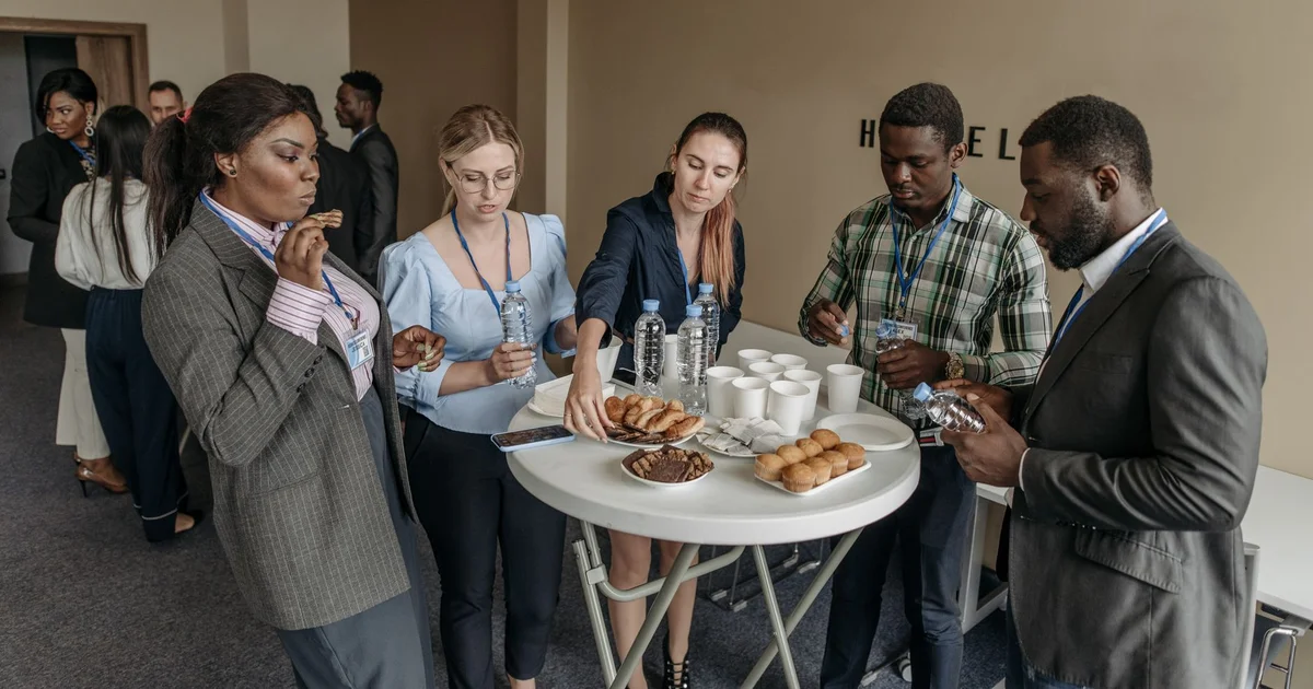 Attendees at an event chatting and having refreshments around a table