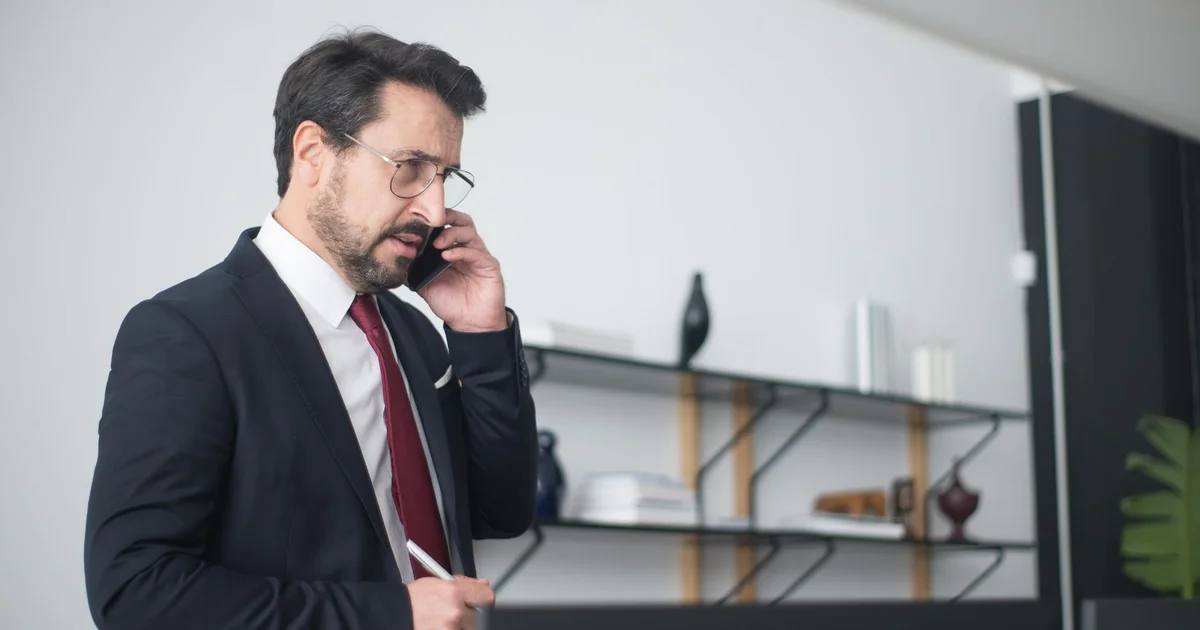 Empresario hablando por teléfono celular con expresión preocupada en una oficina