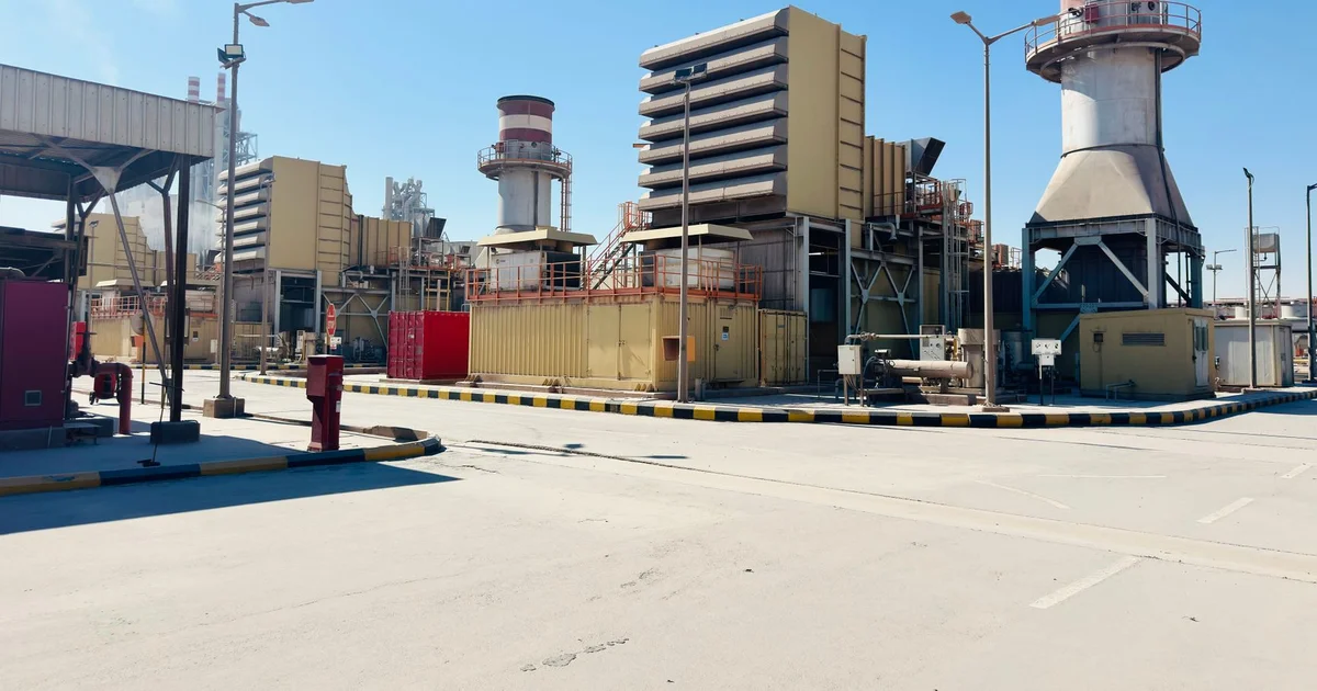 Central de generación eléctrica con turbinas, chimeneas y edificios industriales bajo un cielo despejado