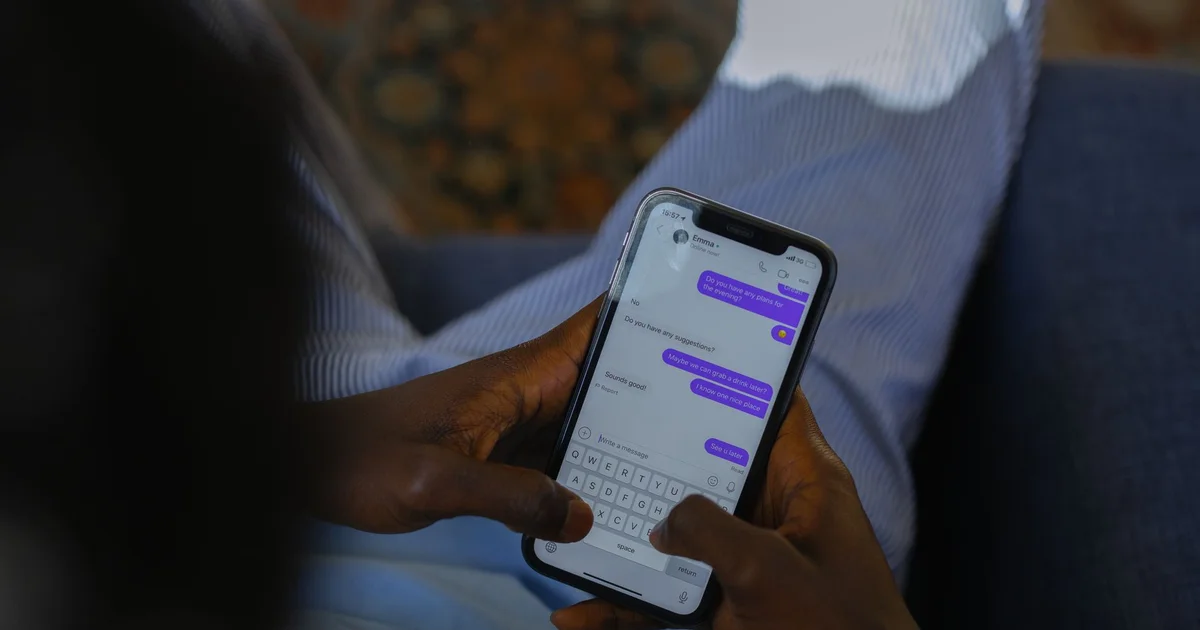 Manos sosteniendo un teléfono y escribiendo en una conversación de chat