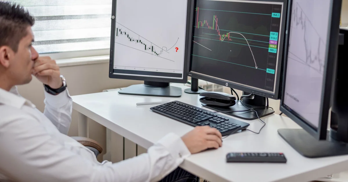 Profesional analizando gráficos de datos en varios monitores en su puesto de trabajo